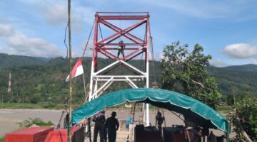Babinsa dan Warga Bersama Sama Gotong Royong Cat Tiang Pylon Jembatan Gantung Perintis