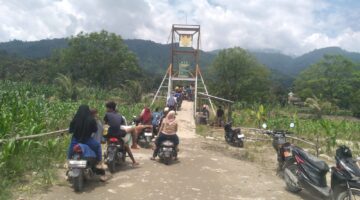 Babinsa bersama Bhabinkamtibmas Bantu Atur Penyeberangan Warga melintasi Jembatan Gantung Perintis