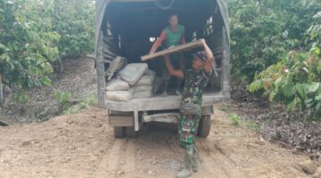 Babinsa Bersama Warga Turunkan Material Semen dan Papan Mal Cor Pondasi Jembatan Gantung Perintis
